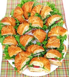 a white plate topped with sandwiches and croissants on top of a table