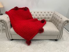 a white couch with a red blanket on it