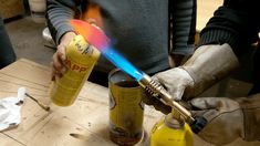 a person holding a lighter over two yellow cans