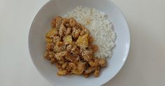 a white bowl filled with rice and some type of food on top of a table