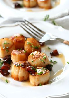 scallops are served on a white plate with a fork