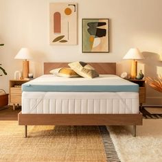 a bed with a wooden frame and mattress in a room next to two lamps on either side of the bed