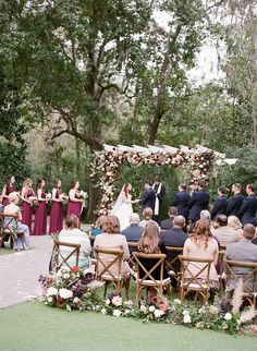 an outdoor wedding ceremony with people sitting at the alter and one person standing in front of them