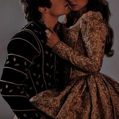 a man and woman kissing each other while dressed in period clothing