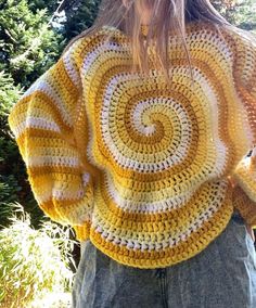 a woman wearing a yellow and white crochet sweater with a spiral design on it