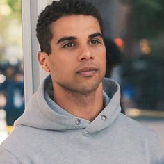 a young man in a gray hoodie looking at the camera with a serious look on his face