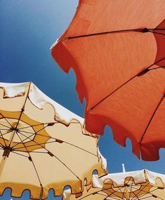 several orange and yellow umbrellas against a blue sky