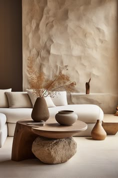 a living room filled with furniture and a large stone wall behind the white couches