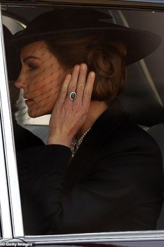 the woman is wearing a black hat and holding her hand up to her face as she sits in a car