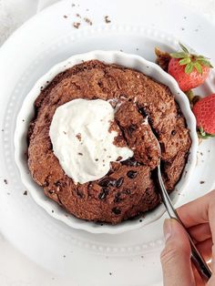 a chocolate cookie with whipped cream in a bowl on a plate next to strawberries