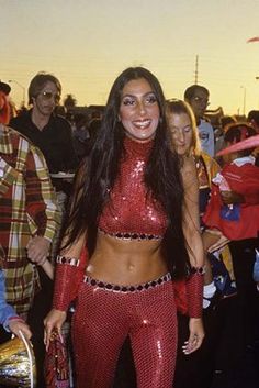 a woman in red and silver outfit standing next to other people