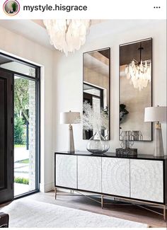 a white and black dresser with two mirrors on it's sideboard next to a door