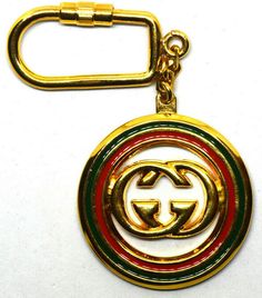 a gold metal key chain with a gucci logo in the center on a white background