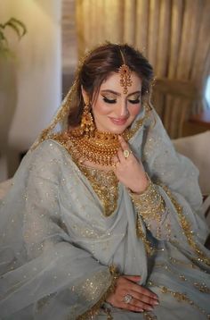 a woman in a bridal outfit sitting on a couch with her hand under her chin