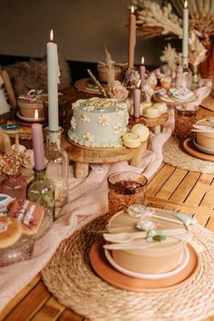 a table topped with lots of cake next to candles and other food on top of plates