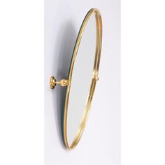 an oval mirror mounted to the side of a wall next to a hook on a white wall