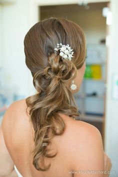 the back of a woman's head with long hair and flowers in her hair