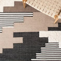 an area rug with black, beige and white designs on it next to a chair