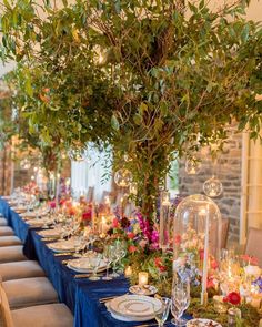 a long table with blue linens and flowers on it is set for an elegant dinner