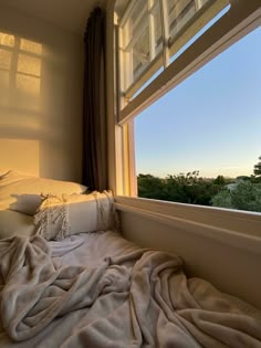 an unmade bed sitting in front of a window