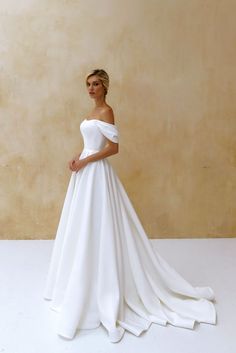 a woman in a white wedding dress posing for the camera with her hand on her hip