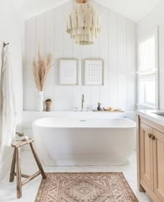 a large white bath tub sitting next to a wooden stool