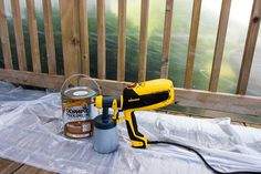 a paint sprayer sitting on top of a white sheet next to a can of brown liquid