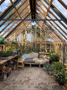 the inside of a greenhouse with lots of potted plants and furniture in front of it