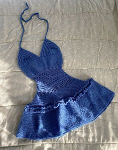 a crocheted blue dress laying on top of a bed