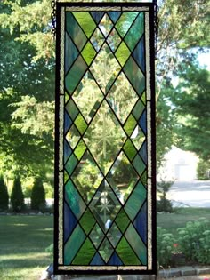 a stained glass window hanging from the side of a tree in front of a house