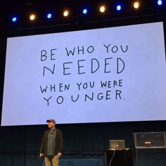 a man standing in front of a large screen with writing on it that says be who you needed when you were younger