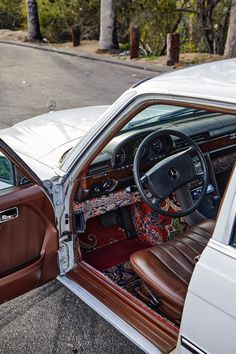 the interior of a white car with brown leather trims and an ornate carpeted floor