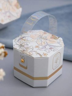 a white box with gold trim and flowers on the inside is sitting on a table