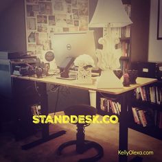 a desk with a computer on it in front of a book shelf filled with books