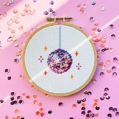 a cross - stitch pattern on a pink background with sequins