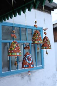 a group of bells hanging from the side of a building next to a blue window