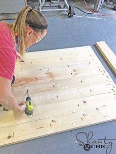 a woman using a drill to attach wood planks