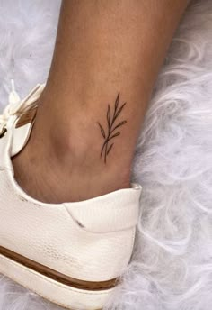 a woman's foot with a small plant tattoo on the side of her ankle