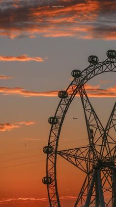 a ferris wheel with the sun setting in the background