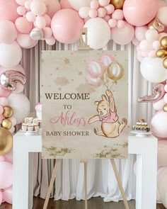 a baby shower sign surrounded by balloons and streamers in pink, gold and white