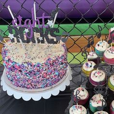 a table topped with lots of cupcakes covered in frosting and sprinkles