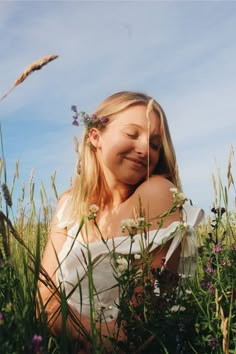 a woman sitting in the middle of a field with wildflowers on her head