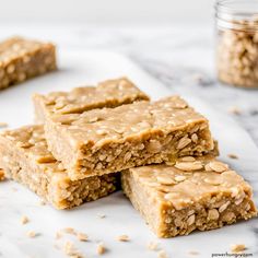 peanut butter granola bars stacked on top of each other with oats scattered around them