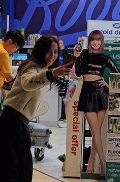 a woman taking a photo with her cell phone in front of a display at an electronics store