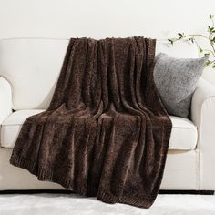 a white couch with a brown blanket on it