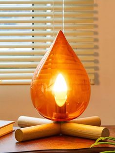 an orange light bulb sitting on top of a wooden table next to some pencils