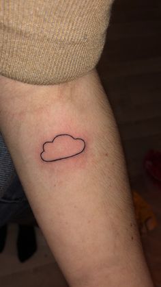 a small black cloud tattoo on the arm