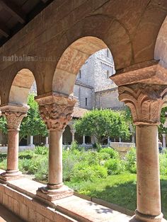 an old building with stone pillars and arches in front of the building is surrounded by greenery