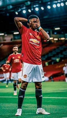 a man standing on top of a soccer field holding his hands to his face while wearing a red shirt