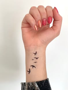 a woman's arm with birds on it and her hand holding up the wrist